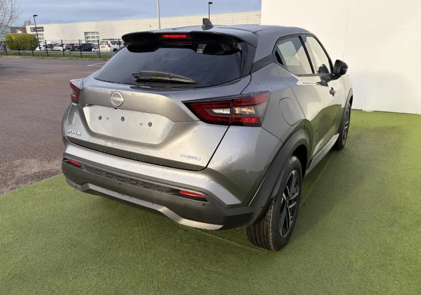 Vue 3/4 arrière droite d'un Nissan Juke II hybride gris métallisé avec feux LED et jantes alliage noires.