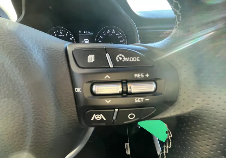 Gros plan sur les commandes au volant à droite de la Kia Rio noire 2021, avec affichage du tableau de bord en arrière-plan.