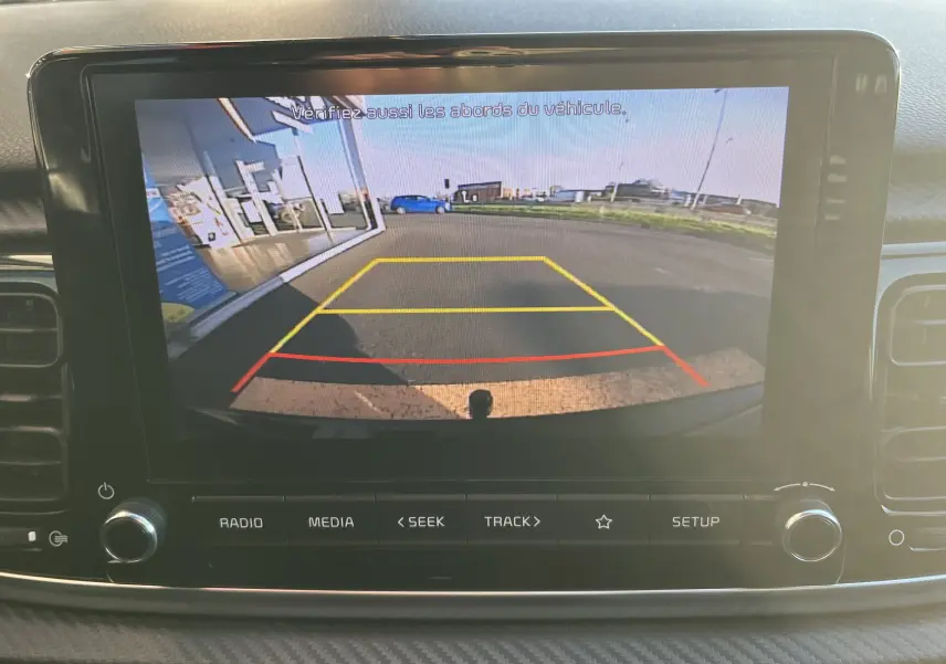 Vue de l'écran de la caméra de recul d'une KIA RIO noire 2021, affichant les lignes de guidage colorées arrière.