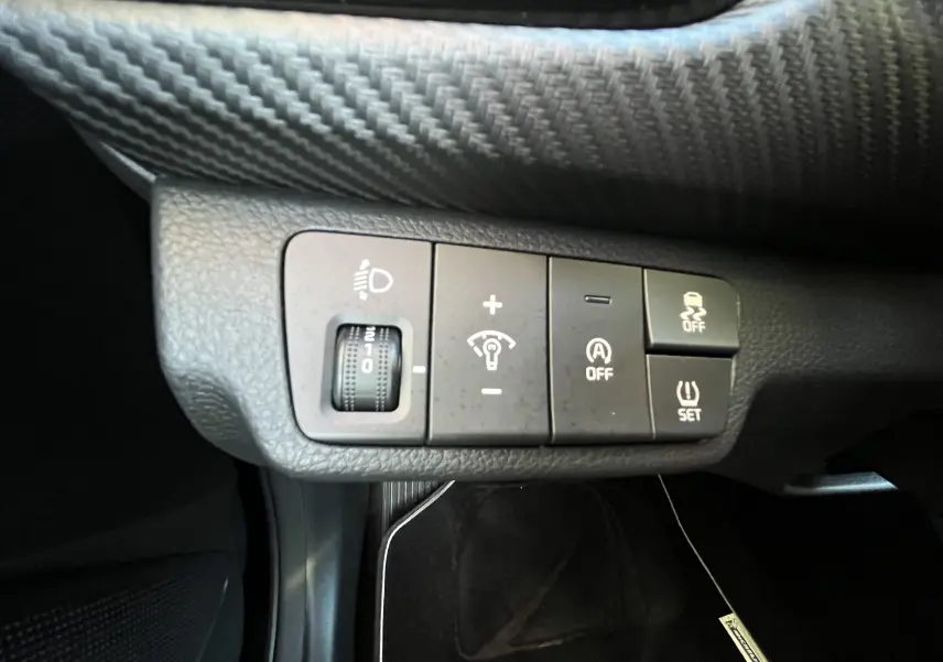 Gros plan sur les commandes de réglage d’éclairage et d’assistance du tableau de bord d’une Kia Rio noire 2021.