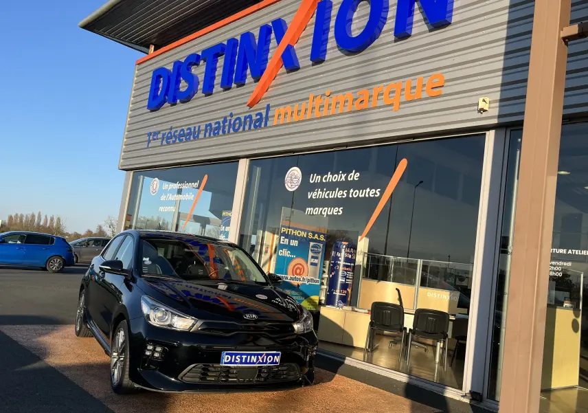 KIA Rio 1.0 GDI 100 Hybrid GT Line noire vue de face en léger 3/4, garée devant un showroom Distinxion.