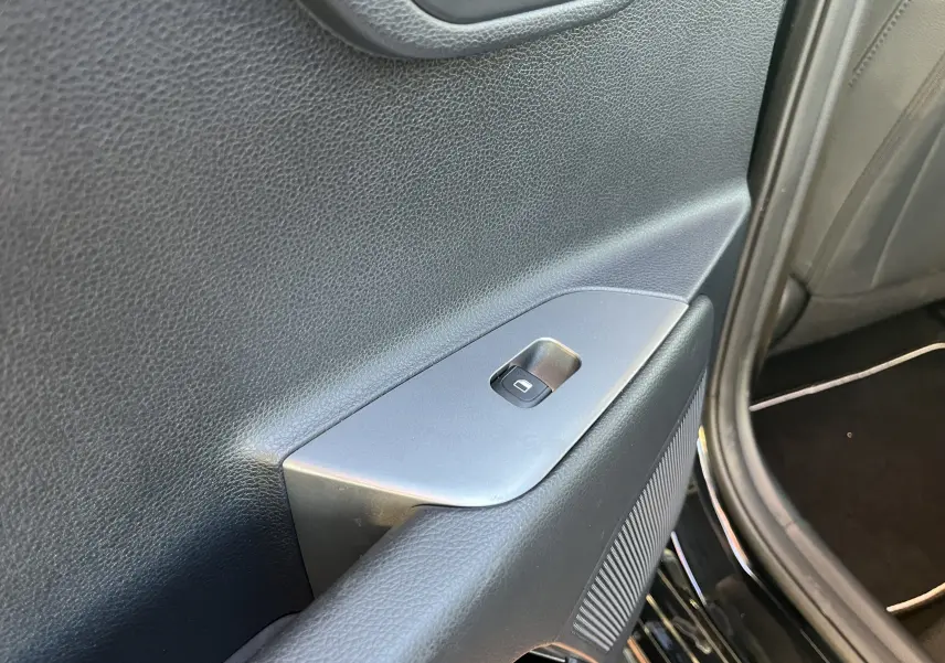 Gros plan sur la commande de lève-vitre arrière droite dans l’habitacle noir d’une KIA Rio 1.0 GDI 100 Hybrid GT Line 2021.