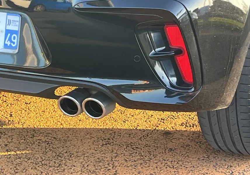 Gros plan sur l'arrière droit noir de la KIA RIO 1.0 GDI 100 HYBRID GT LINE 2021 avec double sortie d'échappement et feu rouge.