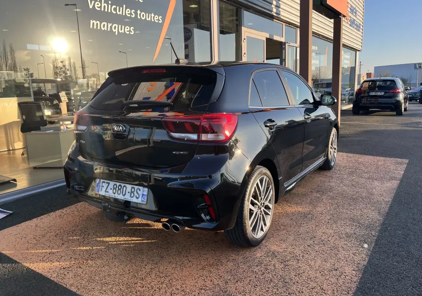 Vue 3/4 arrière droite d'une KIA Rio noire 2021 GT Line avec double sortie d'échappement et jantes alliage 17 pouces.