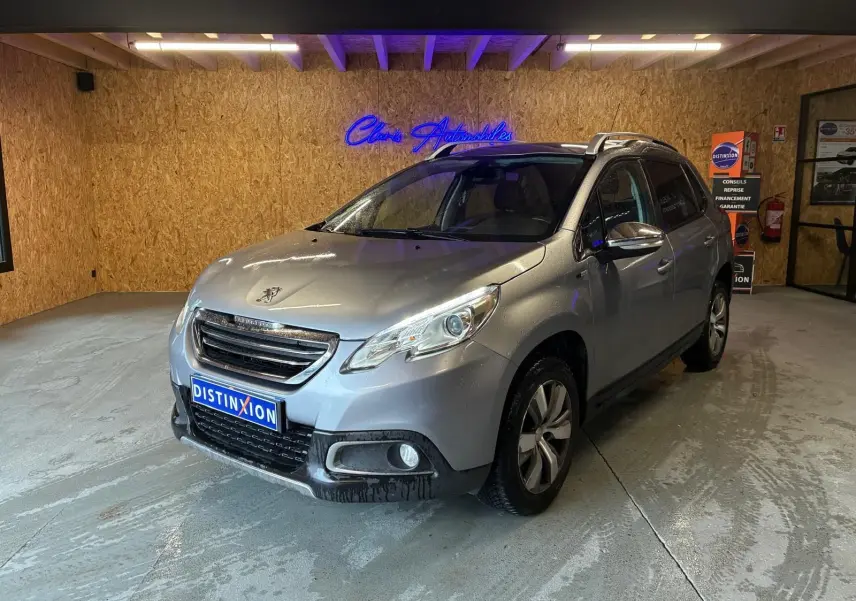 Peugeot 2008 gris vue 3/4 avant droit dans un garage avec toit ouvrant et jantes alliage.