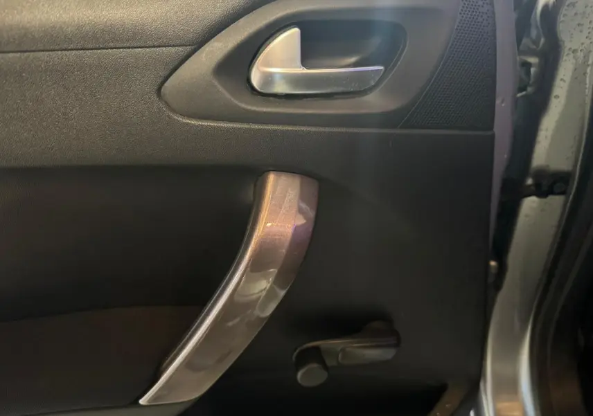 Détail de la poignée intérieure de porte côté gauche du Peugeot 2008 gris 2016 avec manivelle de vitre manuelle.