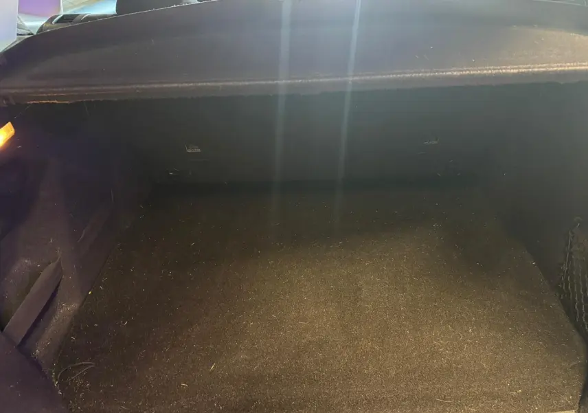 Coffre vide en vue intérieure arrière d'un Peugeot 2008 gris, montrant le tapis de sol et les parois noires.