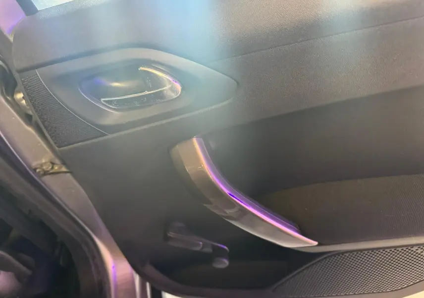 Vue rapprochée de la poignée intérieure côté gauche d’une Peugeot 2008 gris, avec manivelle de vitre manuelle visible.