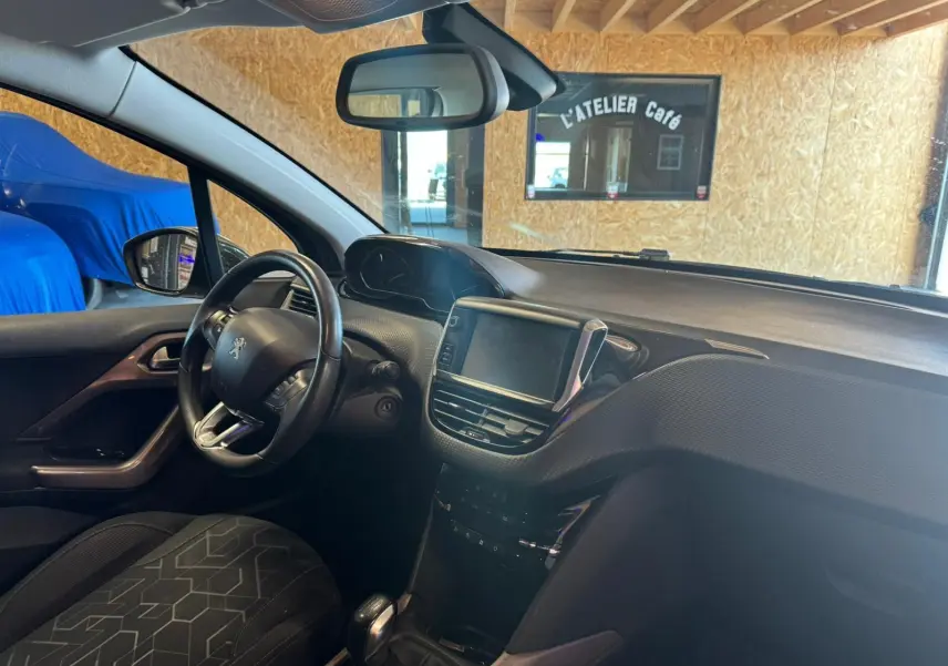 Vue intérieure côté conducteur du Peugeot 2008 gris, mettant en valeur le tableau de bord et l’écran tactile central.