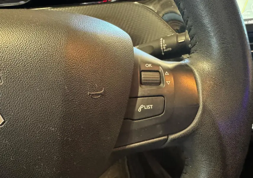 Gros plan sur le volant noir du Peugeot 2008 1.6 HDI 2016 avec commandes intégrées et finition cuir.