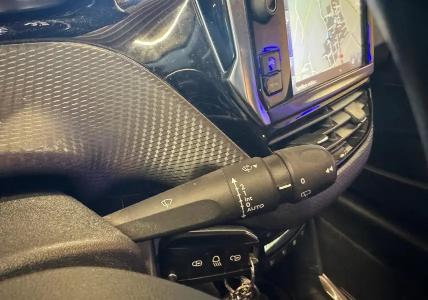 Gros plan sur la commande d'essuie-glace du Peugeot 2008 gris, avec écran GPS et tableau de bord noir en arrière-plan.