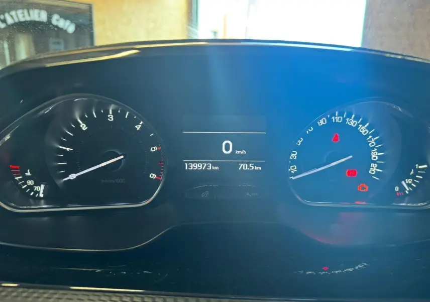 Vue rapprochée du tableau de bord du Peugeot 2008 gris, affichant le compteur à 0 km/h et 139973 km au total.