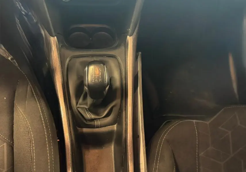 Vue plongeante sur la console centrale du Peugeot 2008 gris, mettant en valeur le levier de vitesse manuel et les sièges en tissu noir.