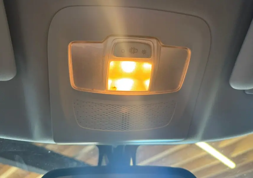 Plafonnier intérieur allumé vu de dessous dans un Peugeot 2008 gris diesel, version 2016, avec toit clair.