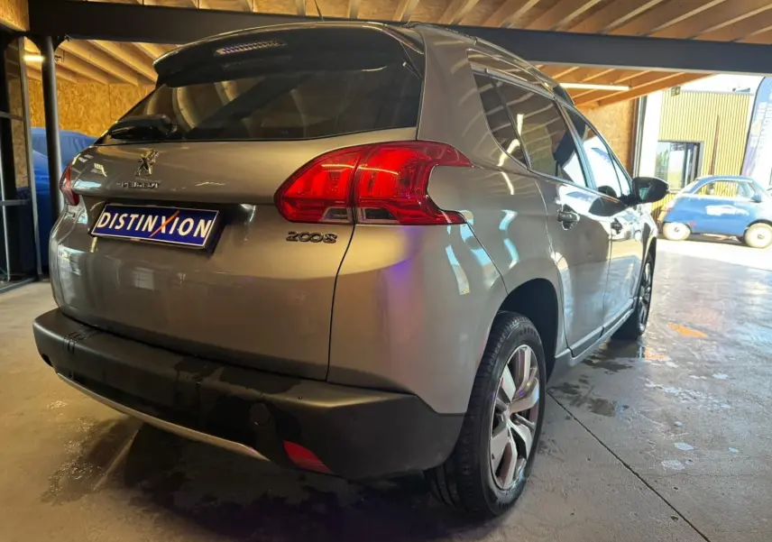 Vue 3/4 arrière droite d’un Peugeot 2008 gris métallisé, avec feux arrière rouges et jantes alliage visibles.
