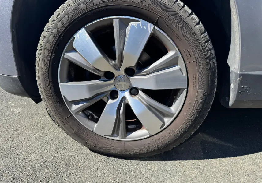Gros plan sur la roue avant droite d’un Peugeot 2008 gris, mettant en valeur la jante alliage et le pneu Goodyear.