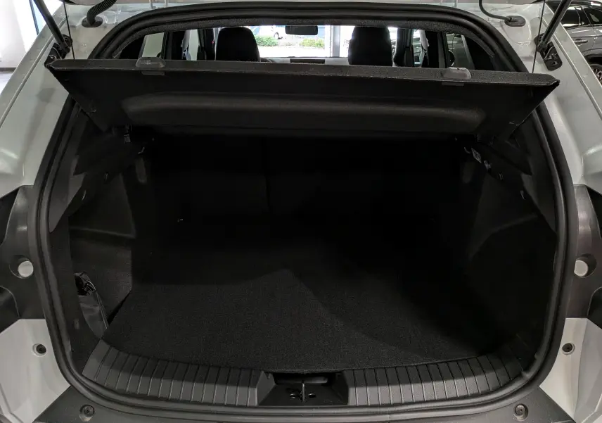 Coffre ouvert vu de l'arrière d'un Dacia Duster blanc Glacier, montrant l'espace de chargement vide et la tablette cache-bagages.