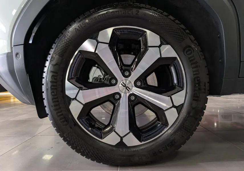 Gros plan sur la roue avant droite du Dacia Duster blanc Glacier, jante alliage bicolore noire et argentée, pneu Continental.