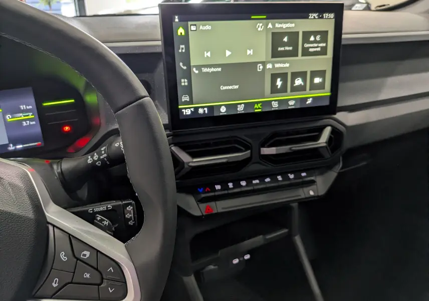 Vue intérieure du tableau de bord du Dacia Duster Hybrid-G 150 CH 4x4, avec écran tactile central et volant partiel visible.