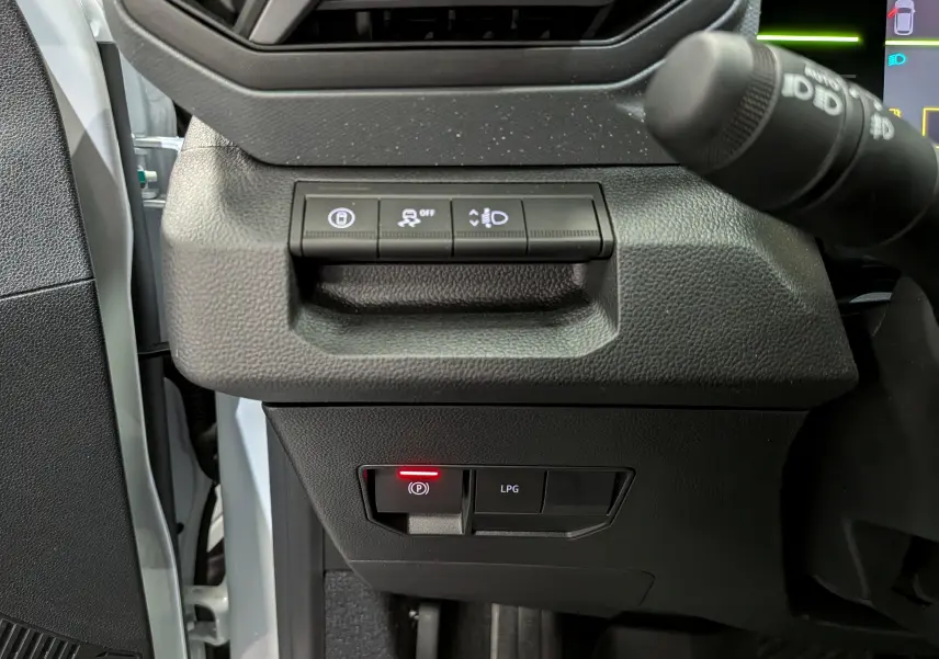Détail intérieur du tableau de bord côté gauche du Dacia Duster blanc Glacier, montrant les boutons de contrôle et l'interrupteur GPL.