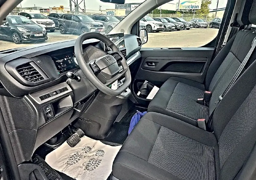 Vue intérieure côté conducteur du Fiat Scudo Combi gris titane, montrant le tableau de bord et la banquette avant noire bi-ton.
