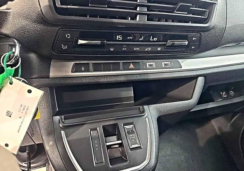 Vue intérieure du tableau de bord et console centrale du Fiat Scudo Combi gris titane, avec commandes climatisation et boîte auto.