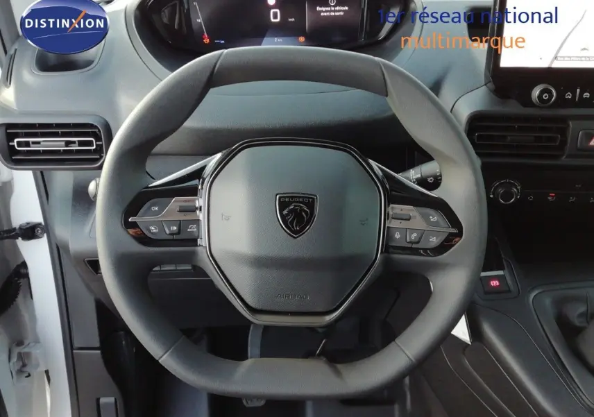 Vue centrée sur le volant du Peugeot Partner blanc Kaolin 2026, avec tableau de bord digital et commandes intégrées.