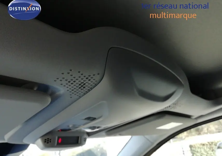 Vue intérieure en gros plan du plafonnier gris clair avec commandes et pare-soleil du Peugeot Partner blanc Kaolin.
