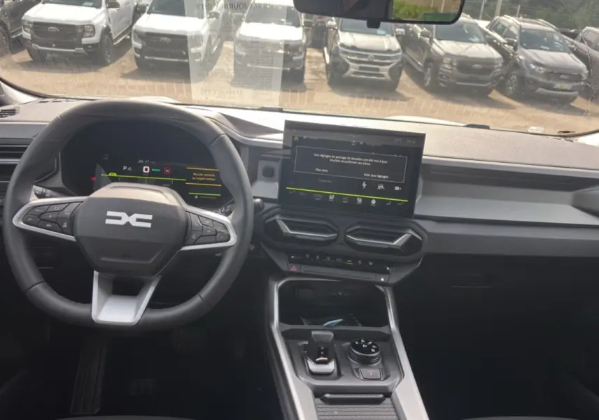 Vue intérieure avant du Dacia Bigster Hybrid 150 avec tableau de bord digital et écran tactile central.
