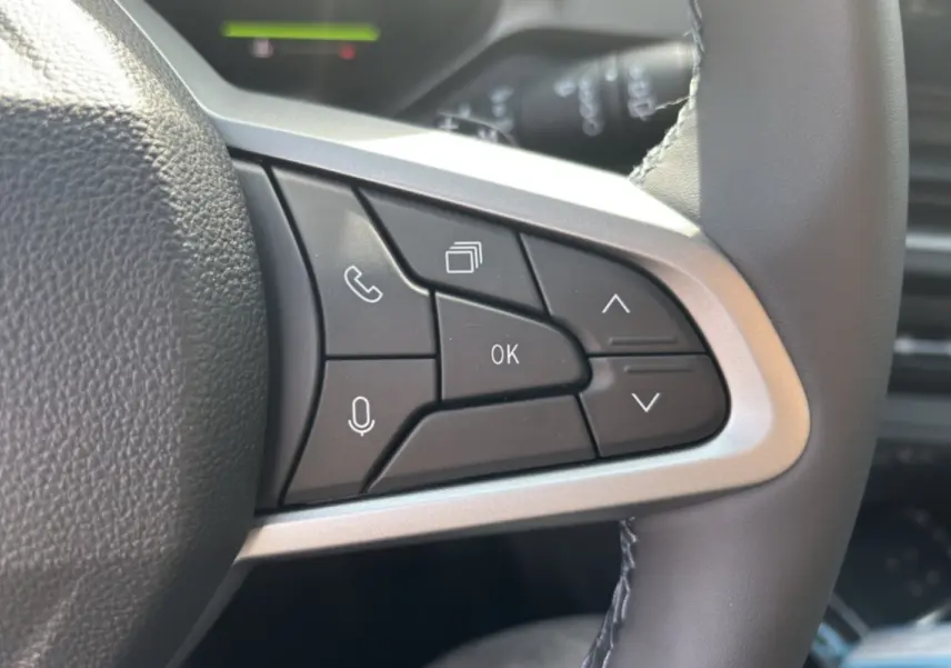 Gros plan sur les commandes multifonctions à droite du volant cuir du Dacia Bigster hybride blanc toit noir.