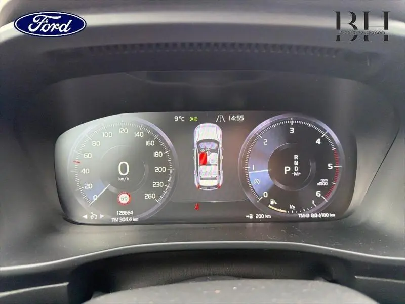 Tableau de bord numérique d'un Volvo XC40 blanc, affichant vitesse, compte-tours et état porte ouverte.