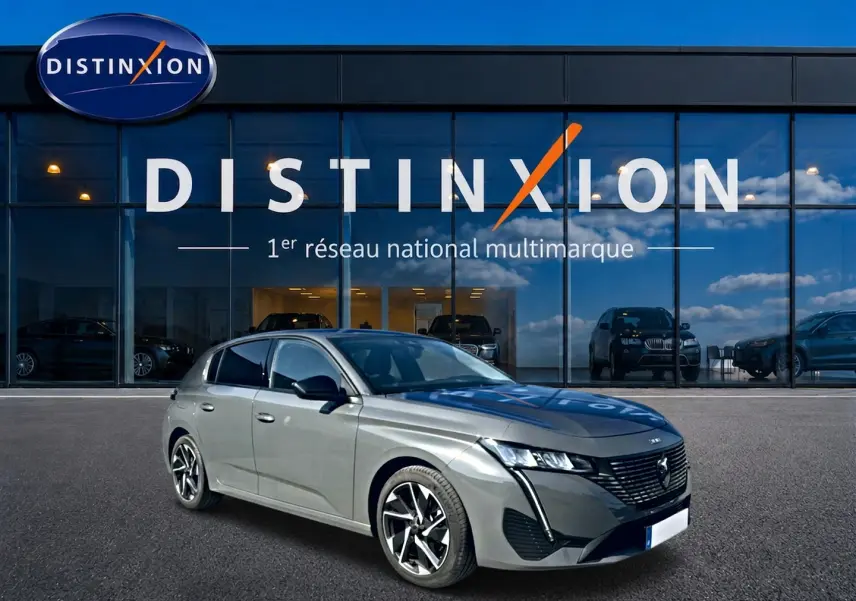 Peugeot 308 gris selenium vue 3/4 avant droit, avec jantes alliage et calandre noire distinctive, devant showroom Distinxion.