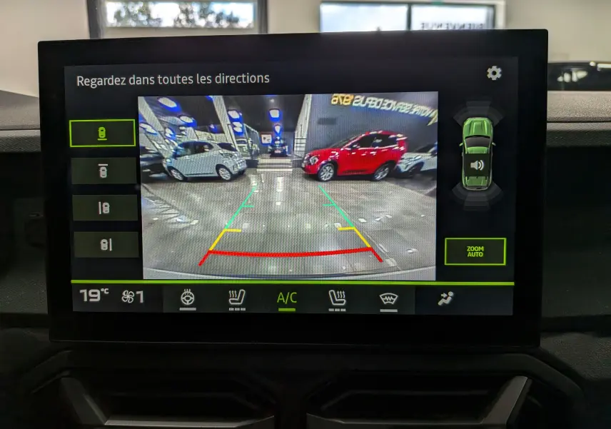Écran intérieur montrant la caméra de recul du Dacia Duster blanc glacier, avec guidage de trajectoire coloré.