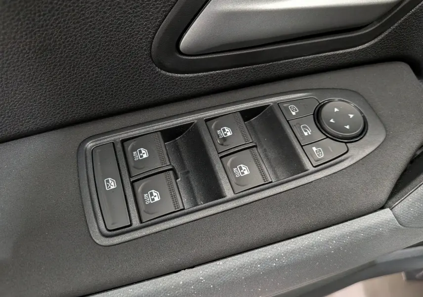 Gros plan sur les commandes de lève-vitres et rétroviseurs côté conducteur du Dacia Duster Hybrid-G 150 CH 4x4, intérieur noir.