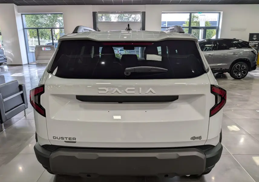 Vue arrière d'un Dacia Duster blanc Glacier 2026 avec logo DACIA et badge 4x4 visible en showroom.