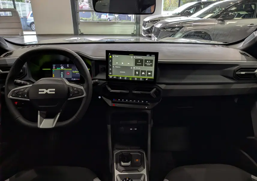Vue intérieure frontale du tableau de bord du Dacia Duster blanc Glacier, avec écran tactile central et volant multifonction.