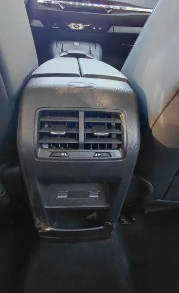 Vue intérieure arrière centrée sur la console centrale noire avec bouches d’aération et ports USB du DS4 Hybride E-Tense 2024.