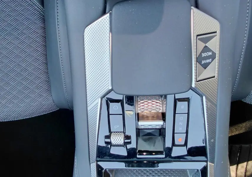 Gros plan sur la console centrale du DS4 hybride gris 2024, avec commandes de boîte automatique et bouton Drive Mode.