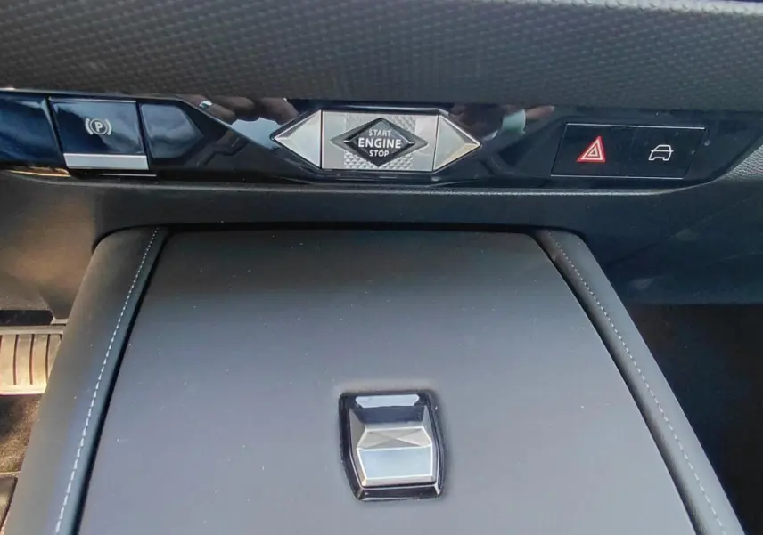 Gros plan sur la console centrale noire du DS4 2024 avec boutons de démarrage, frein à main et alertes.