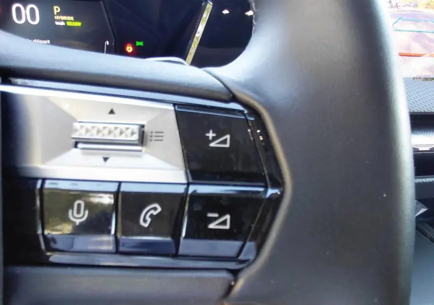 Gros plan sur les commandes au volant du DS4 Hybride E-Tense 225, avec écran tactile et caméra de recul visibles.