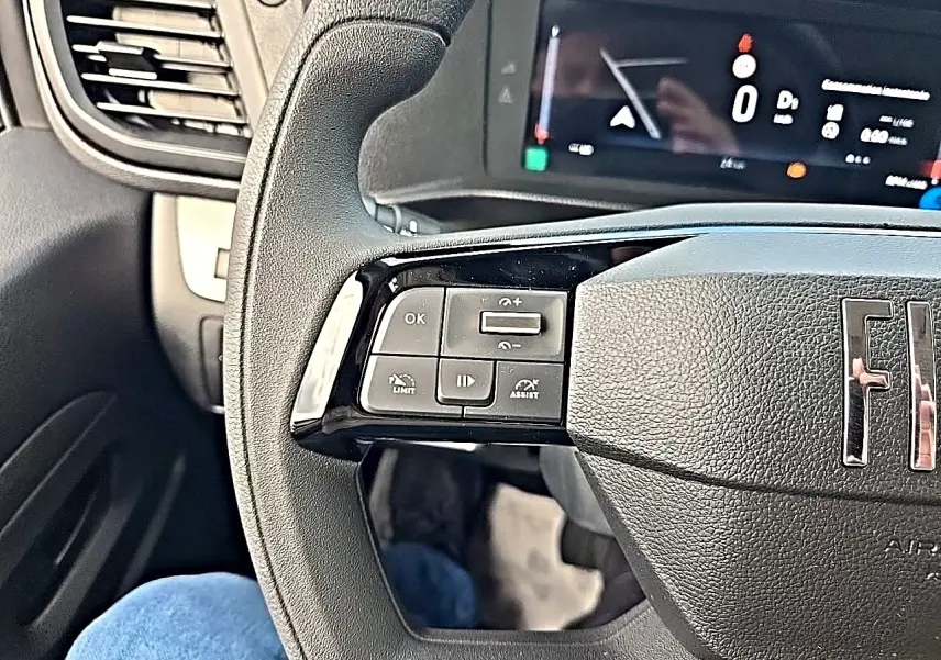 Gros plan sur le volant noir du Fiat Scudo Combi avec commandes multifonctions à gauche et tableau de bord numérique.