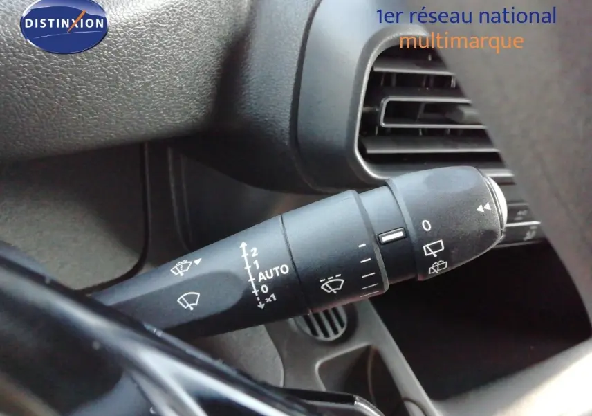 Gros plan sur la commande d'essuie-glace à gauche du volant dans l'habitacle sombre du Peugeot Partner blanc Kaolin.