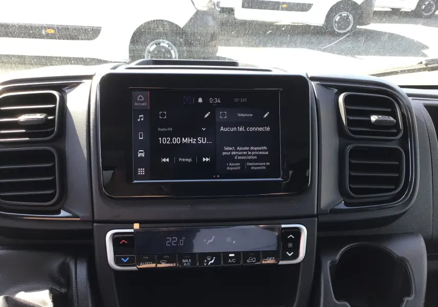 Vue intérieure centrée sur l'écran tactile et la console de climatisation du FIAT Ducato Chassis Benne blanc 2023.