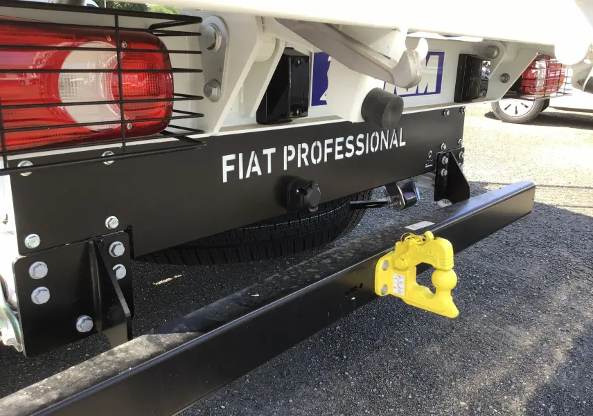 Gros plan arrière droit du FIAT Ducato Chassis Benne blanc avec attelage jaune et protection des feux.