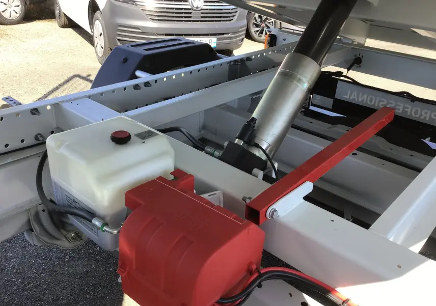 Gros plan sur la benne acier blanche du Fiat Ducato Chassis Benne 3T5, montrant le vérin hydraulique et le coffre rouge.