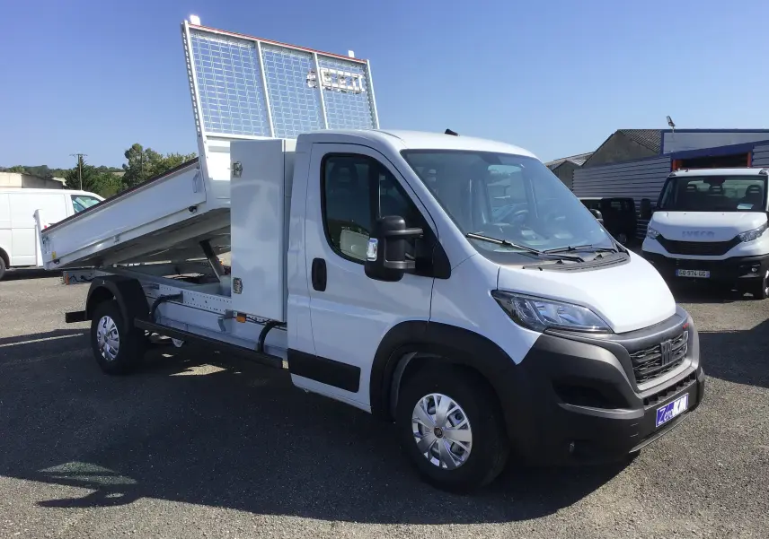 FIAT Ducato Chassis Benne blanc vu en 3/4 avant droit, benne acier relevée et coffre latéral visible.