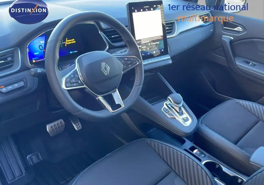 Intérieur avant droit de la Renault SYMBIOZ bleu Iron Metal, tableau de bord moderne avec écran tactile vertical et volant multifonction.