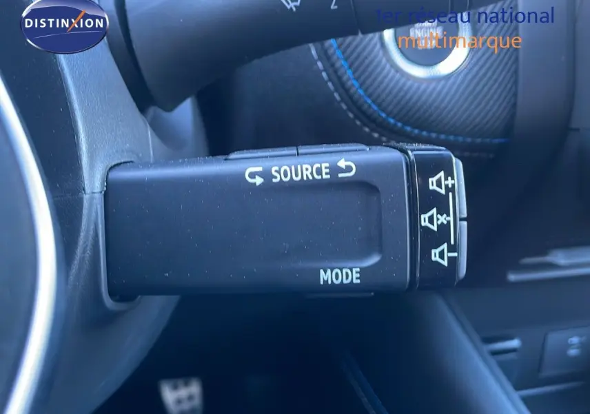 Gros plan sur la commande au volant du Renault Symbioz bleu iron metal, avec boutons source et mode visibles.