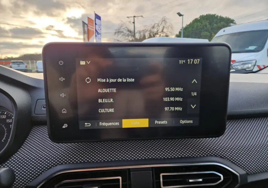Écran tactile central du tableau de bord de la Dacia Sandero blanche 2022, affichant la liste des radios FM.