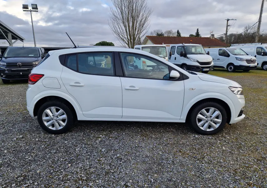 Vue de profil côté gauche d'une Dacia Sandero blanche 2022 bicarburation essence/GPL sur un parking extérieur.